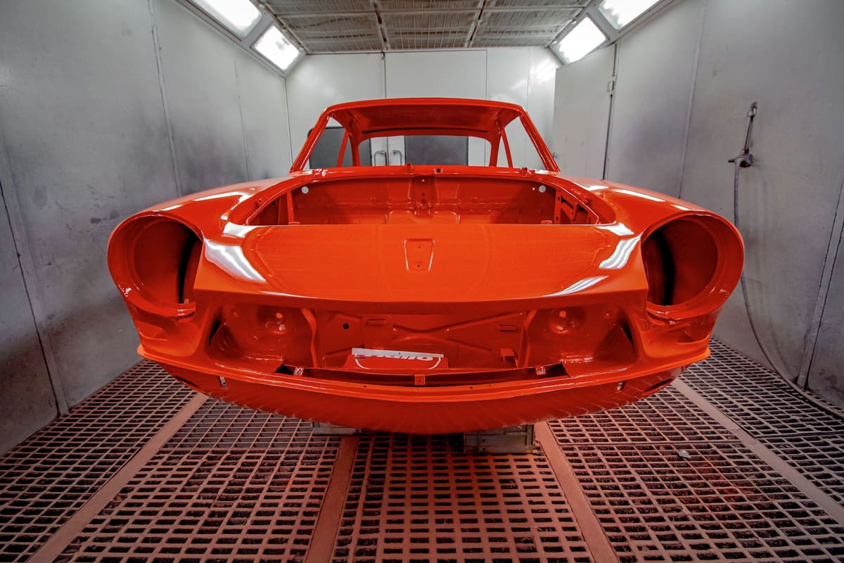 A red car body freshly painted in a paint booth